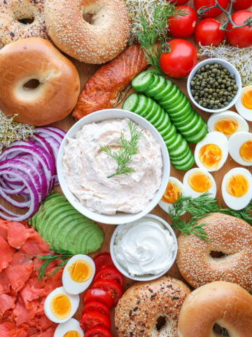 Bagel Board with smoked salmon spread, onions, cucumbers, lox, capers, cream cheese, hard boiled eggs, and tomatoes.