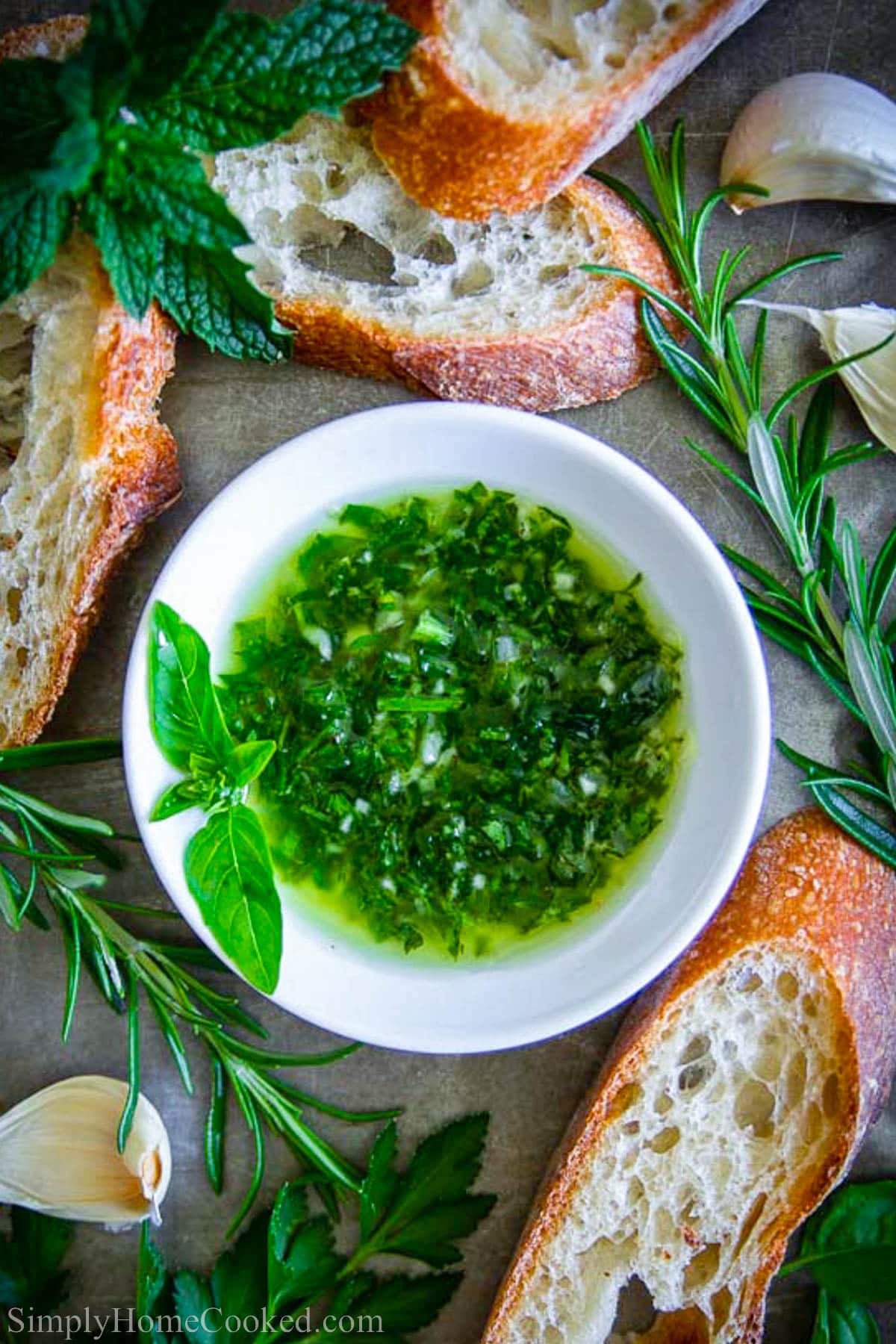 Bowl of Bread Dipping Oil with fresh rosemary and bread nearby.