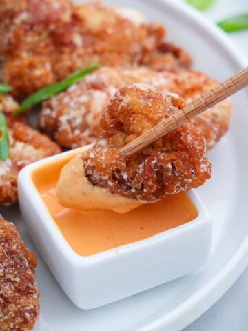 Piece of Chicken Kaarage being dipped into sauce with chopsticks.