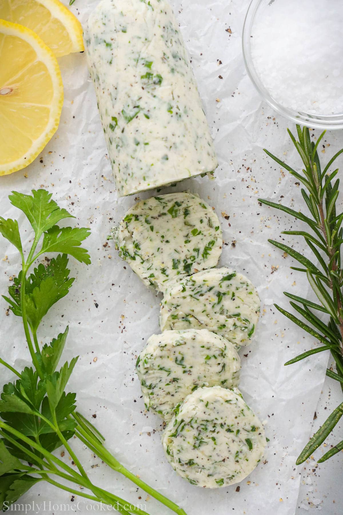 Compound Butter for Steak sliced with parsley and rosemary nearby.