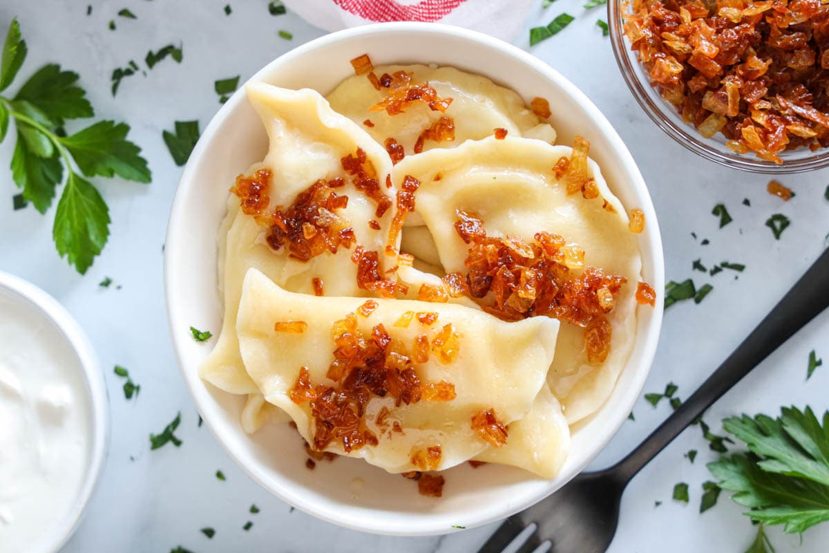 Overview of Potato Pierogi in a bowl topped with bacon bits.