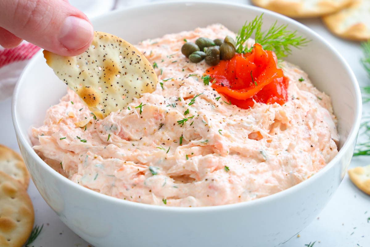 Smoked Salmon Dip in a bowl with a cracker dipping in.