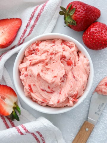 Bowl of Strawberry Butter with a knife and strawberries nearby.