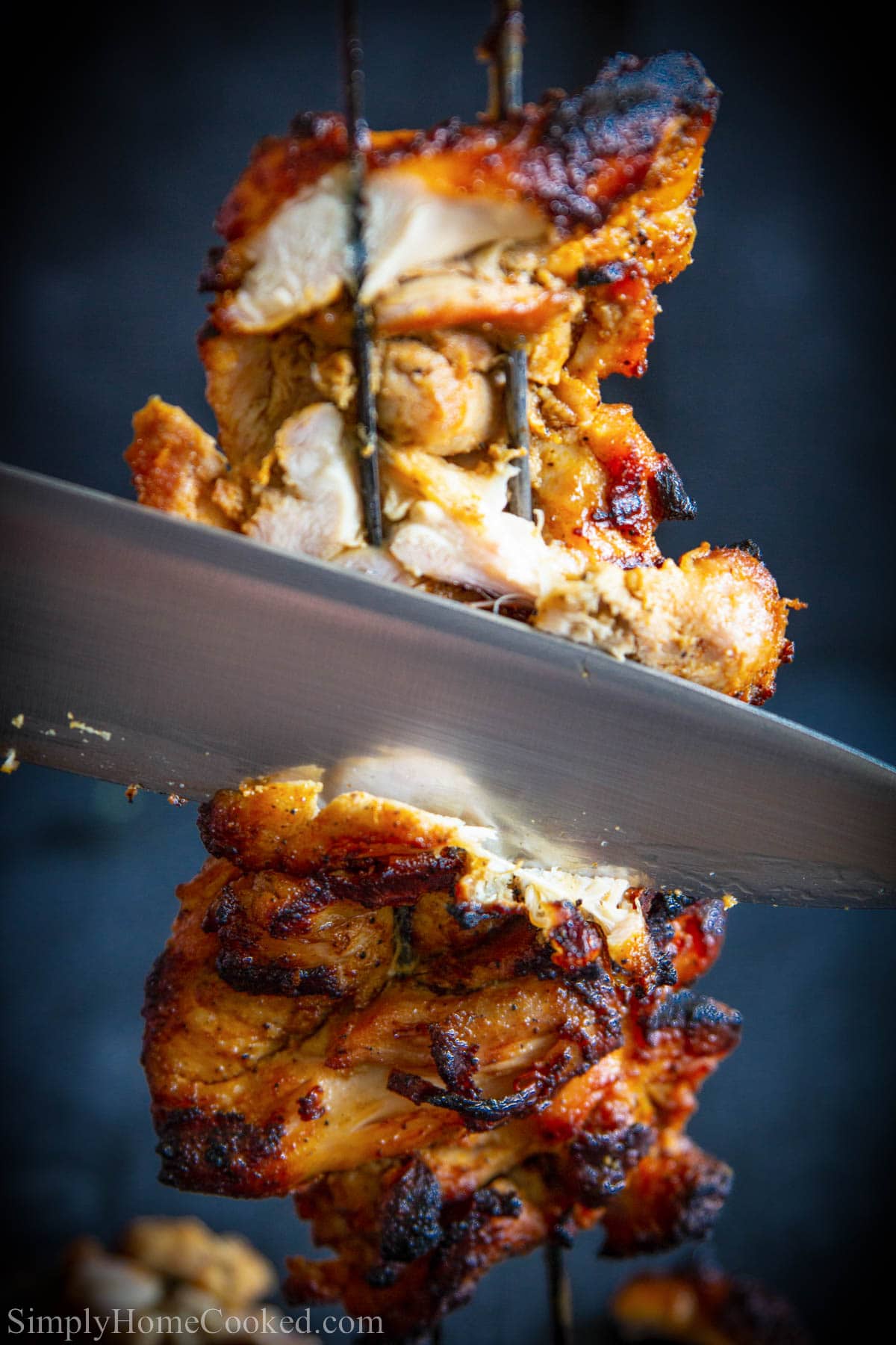 Close up of Chicken Shawarma being cut off metal skewers.