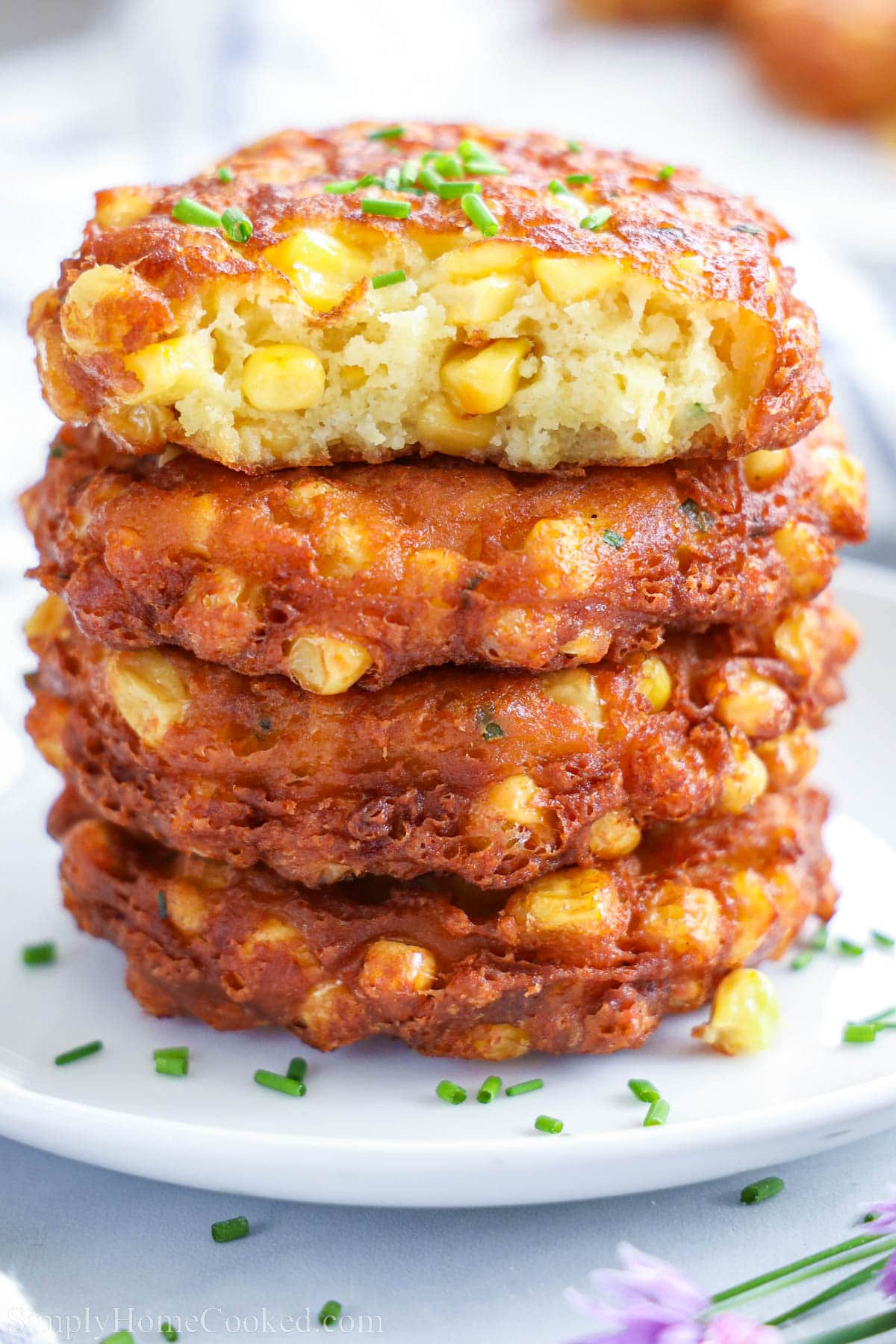 Pile of Corn Fritters, the top one missing a bite. 