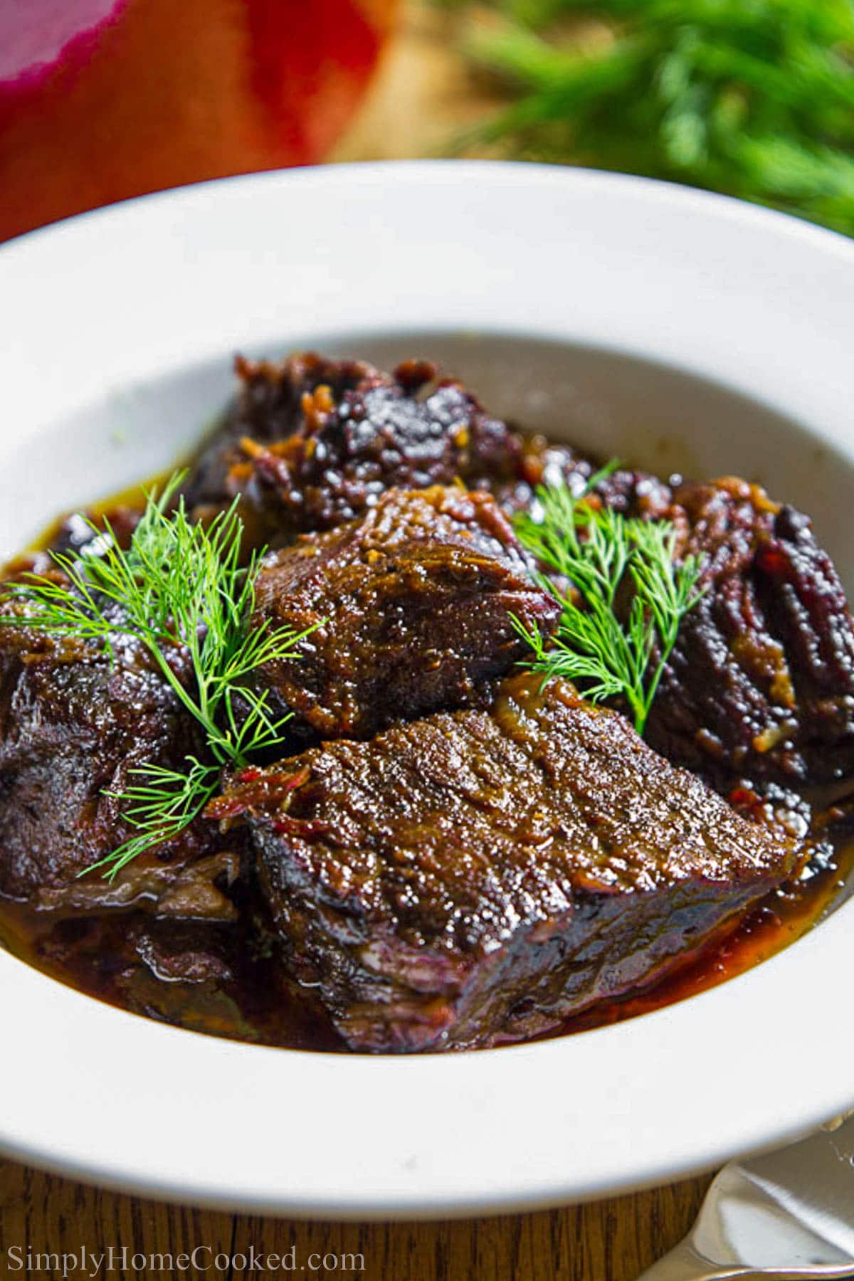 Bowl of Braised Beef topped with fresh herbs.