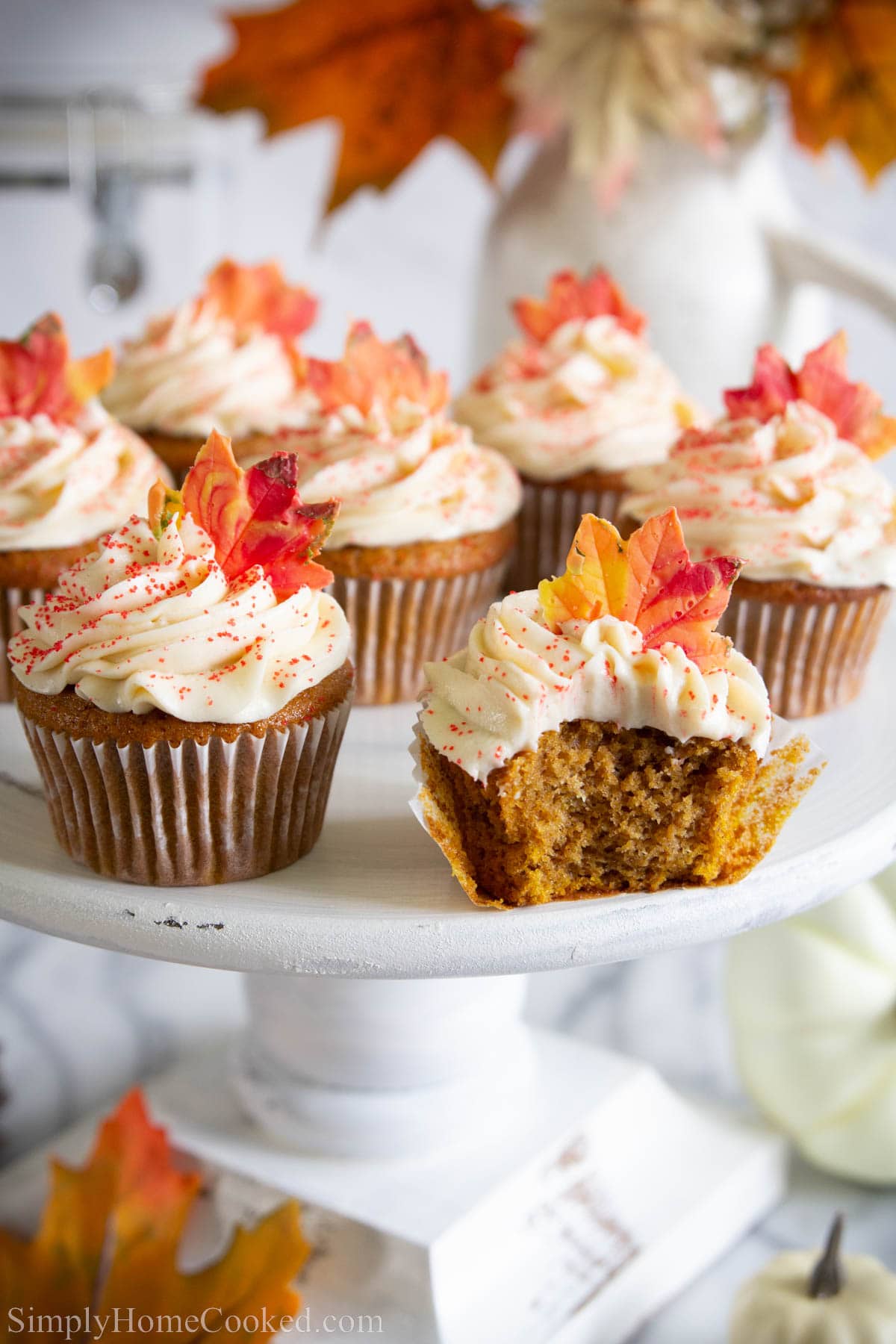 Pumpkin Spice Cupcakes on a stand with one missing a bite. 