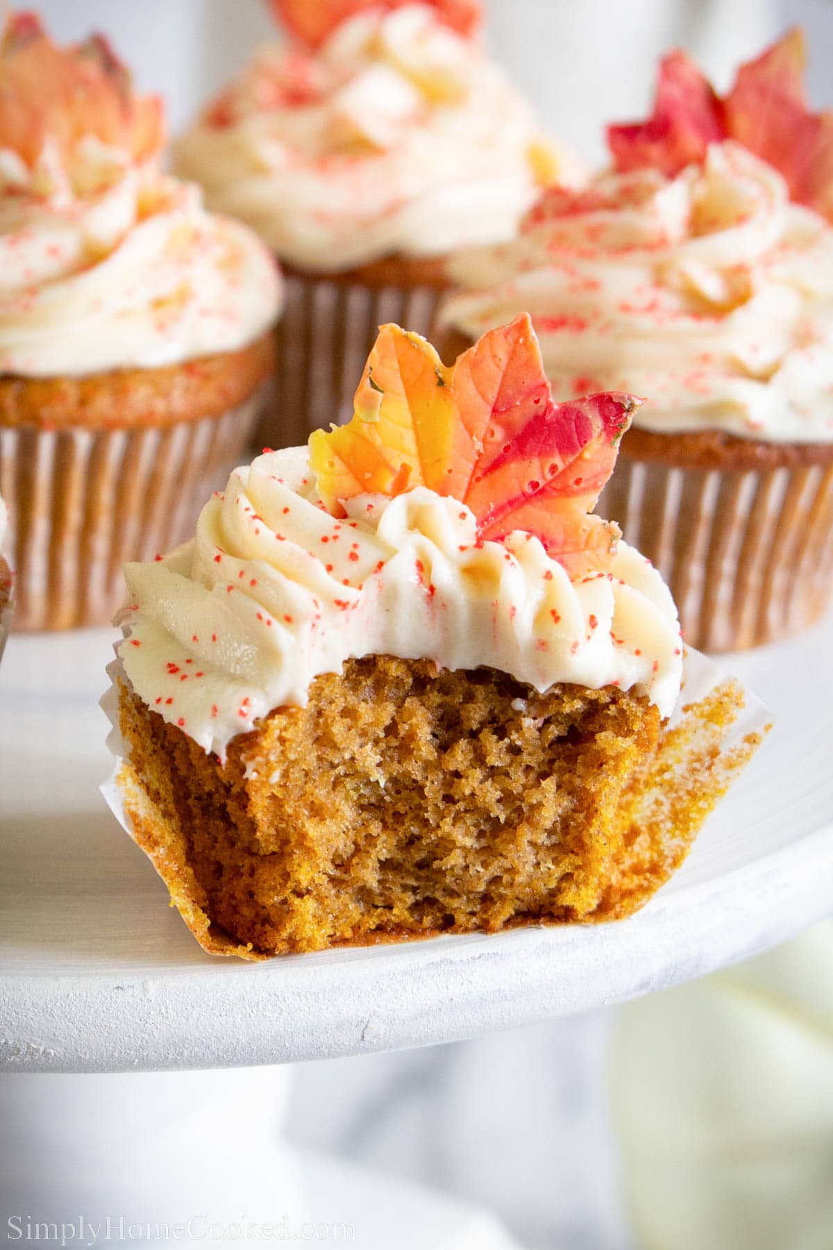 Pumpkin Spice Cupcakes with frosting and candy fall leaves, one missing a bite.