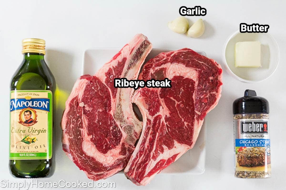 Ingredients for Cooking a Steak in the Oven: olive oil, ribeye steak, garlic cloves, butter, and Weber seasoning.