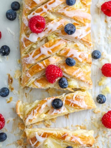 Overhead view of a Cream Cheese Danish covered with fresh blueberries and raspberries.