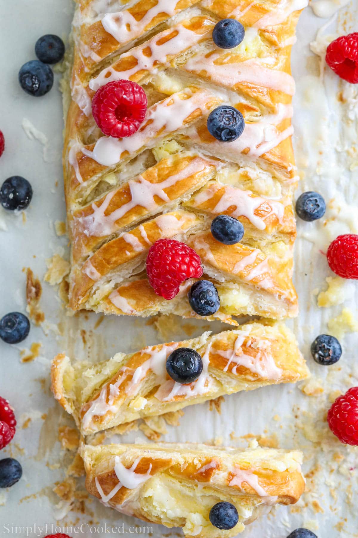 Overhead view of a Cream Cheese Danish covered with fresh blueberries and raspberries. 