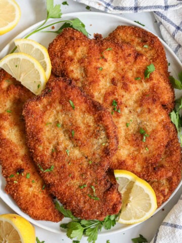 Chicken Cutlets topped with chopped parsley and lemon slices.