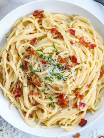 Overview of Spaghetti Carbonara topped with bacon, parmesan, and parsley.