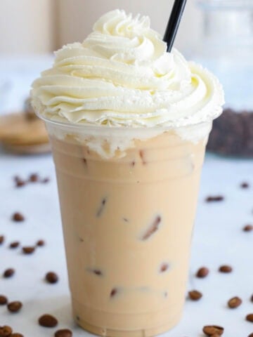 Iced White Chocolate Mocha topped with whipped cream, with a straw.