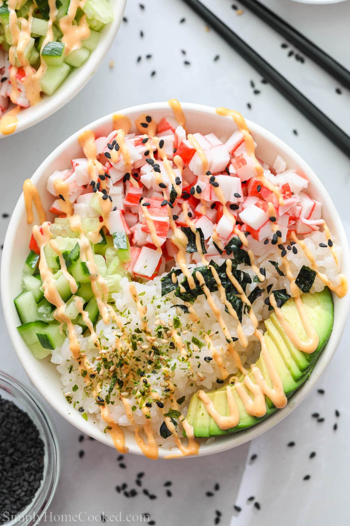 Overview of California Roll Sushi Bowl drizzled with spicy mayo, furikake, and sesame seeds.