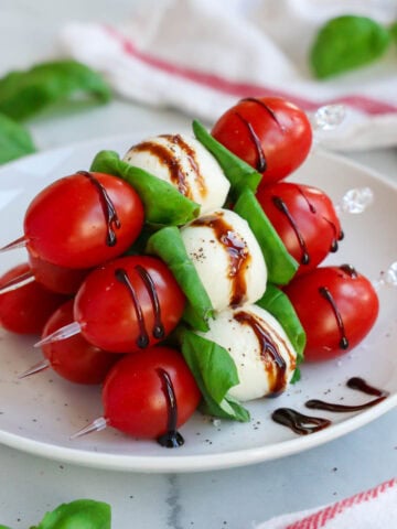 Caprese Skewers in a pile, drizzled with balsamic glaze.