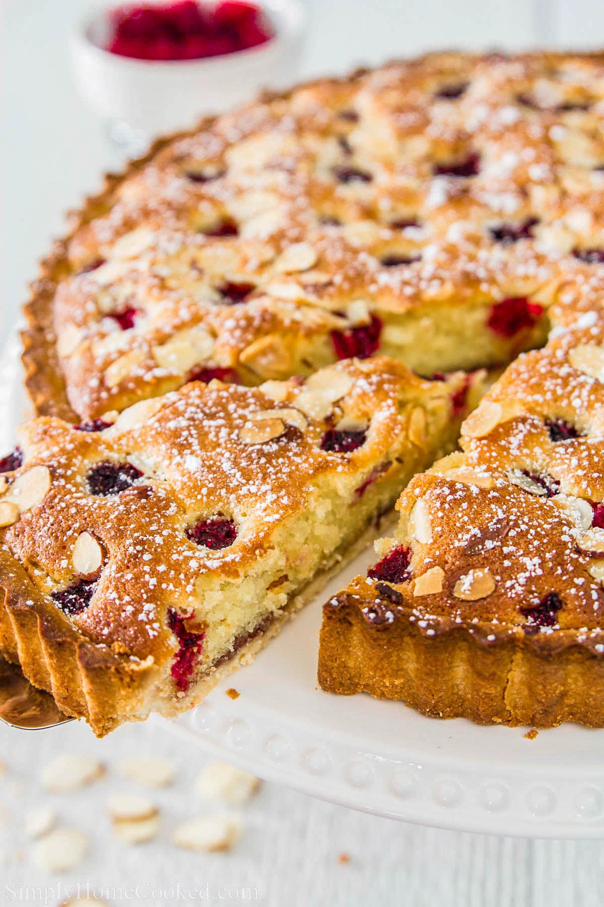 Bakewell Tart with a slice being removed.