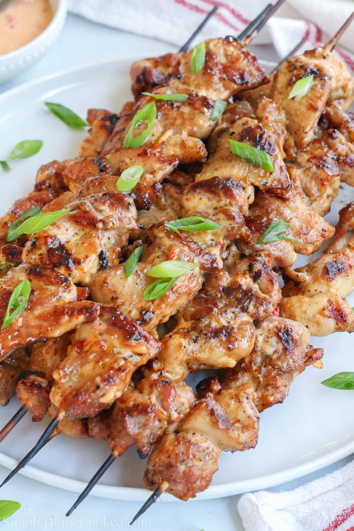 A pile of Bang Bang Chicken Skewers topped with chopped green onions.