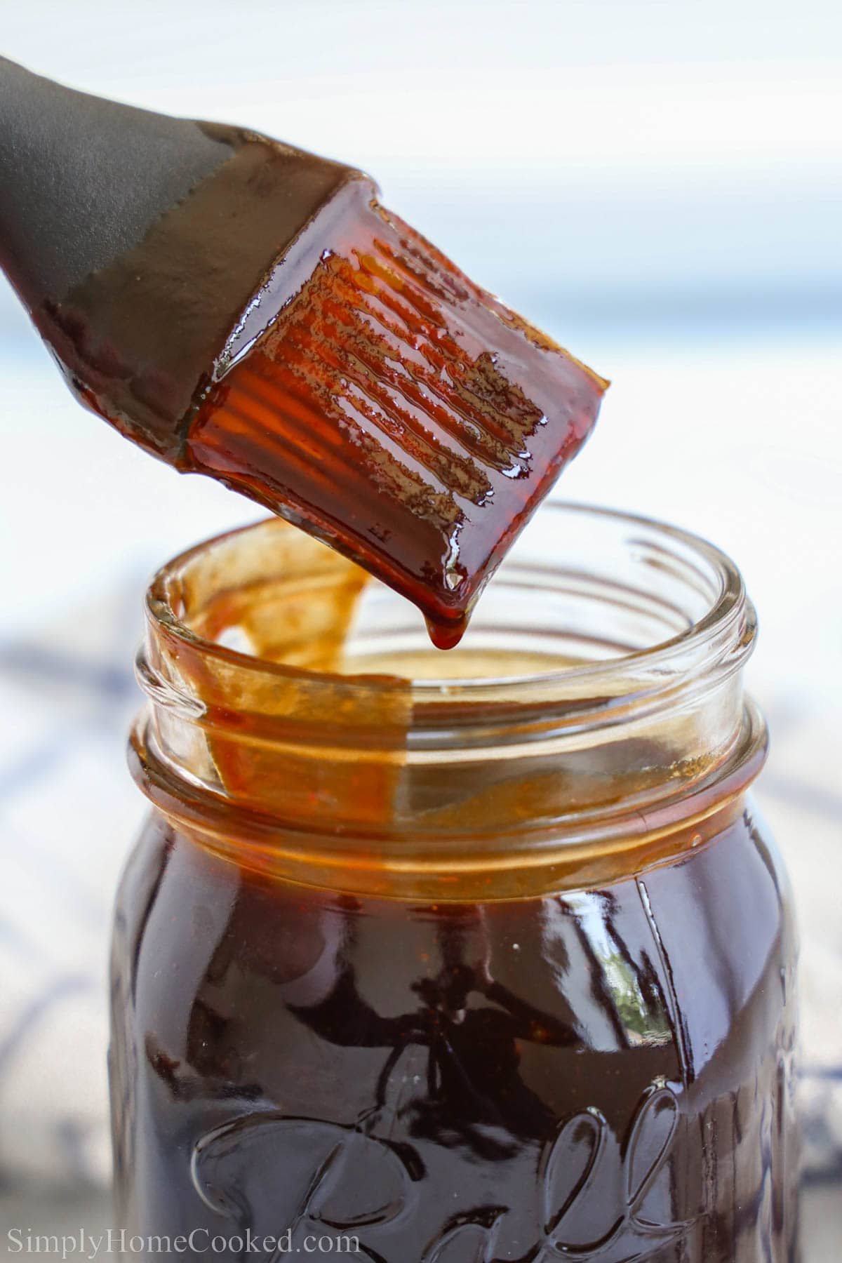 BBQ Sauce in a mason jar with a brush dipped inside.