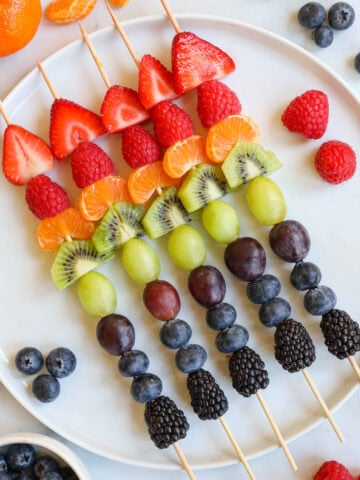 Fruit Kabobs lined up on a plate.