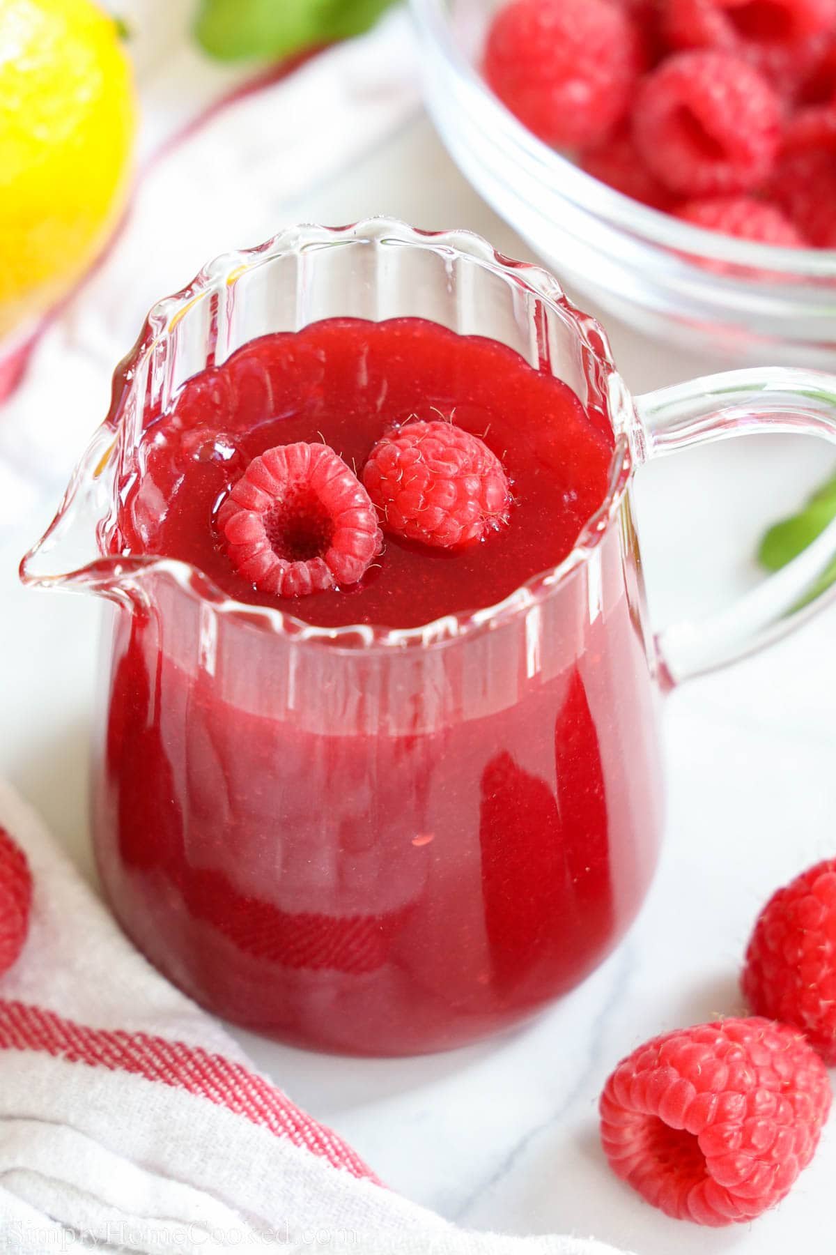Raspberry Coulis in a pitcher with raspberries.