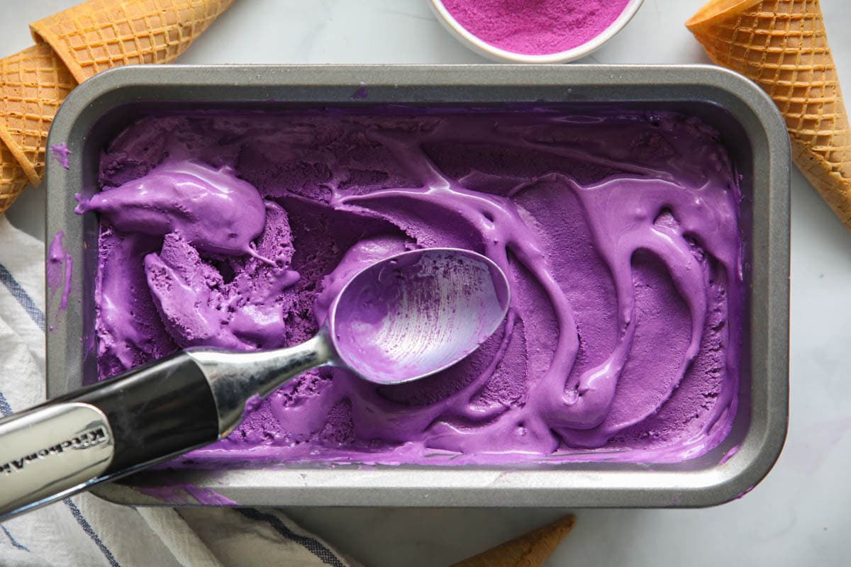 Ube Ice Cream in a pan with a scoop.