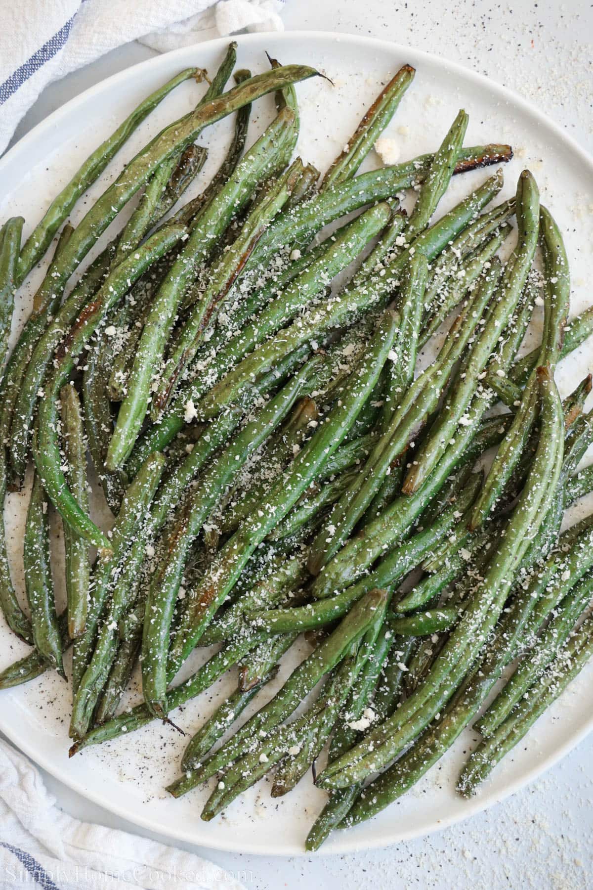 Roasted Green Beans on a plate and topped with parmesan cheese.
