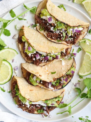 Shredded Beef Tacos lined up on a plate.