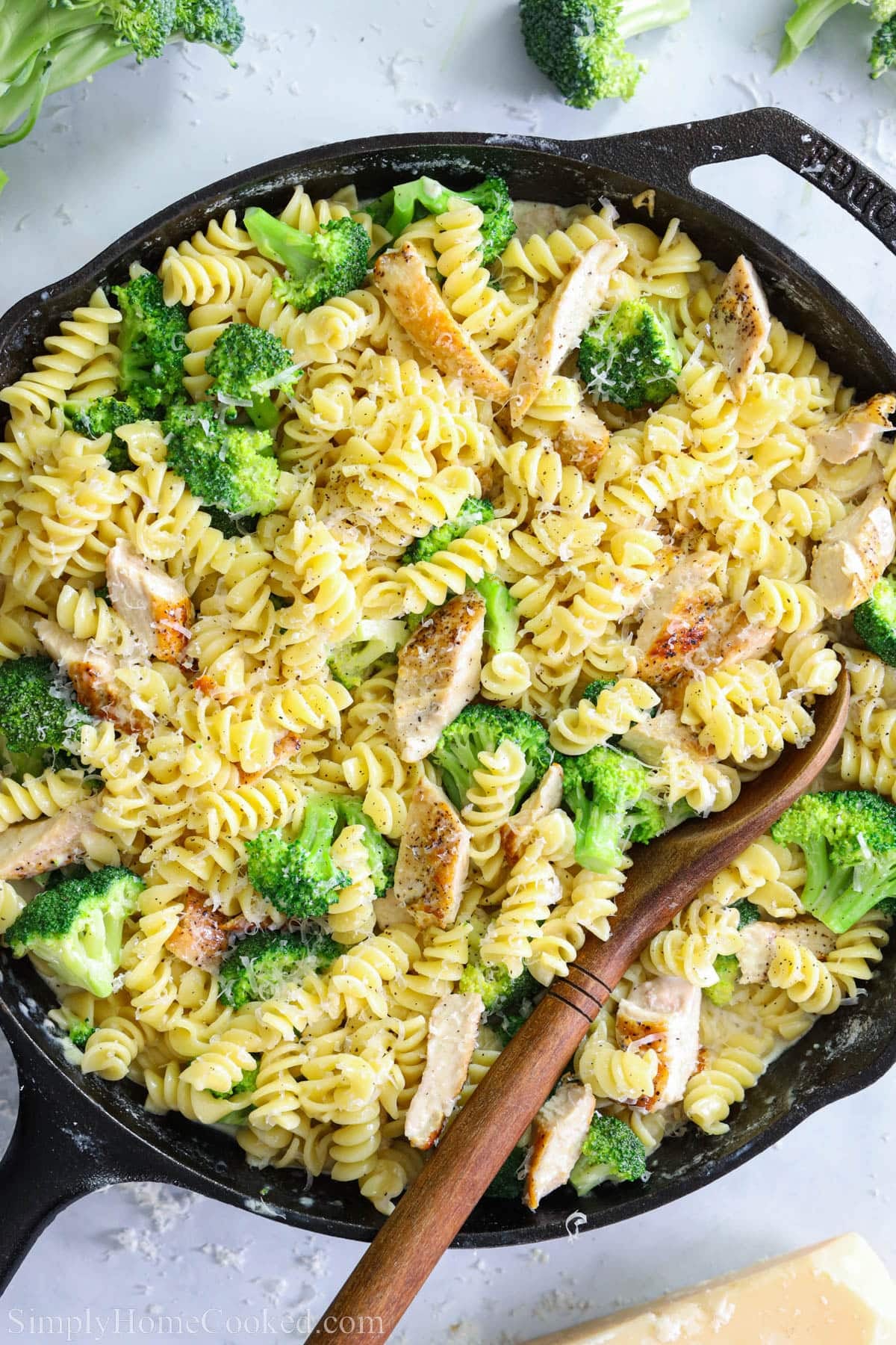 Overhead of Chicken Broccoli Alfredo in a pan with a wooden spoon.