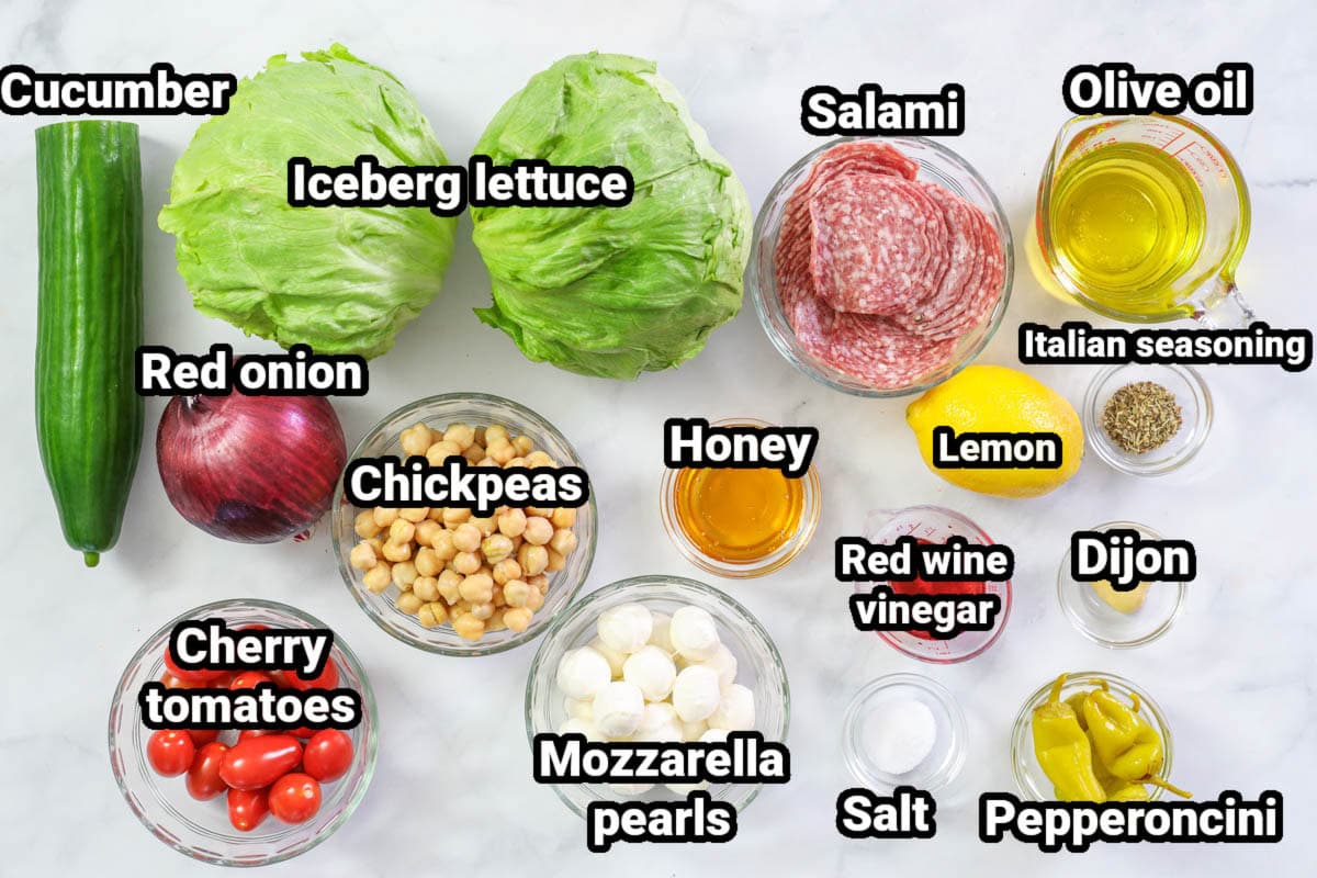 Ingredients for Chopped Italian Salad: cucumber, lettuce, salami, olive oil, Italian seasoning, lemon, Dijon mustard, red wine vinegar, pepperoncini, salt, honey, chickpeas, red onion, cherry tomatoes, and mozzarella pearls.