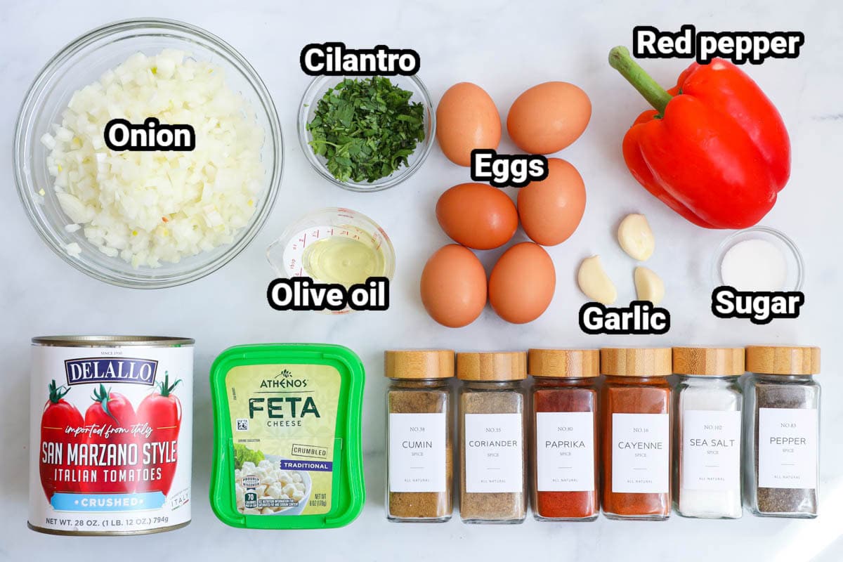 This Middle Eastern egg dish will really make your day. Try this perfectly spiced Shakshuka recipe for breakfast or dinner and you'll discover a new favorite. #easyhomemadeshakshuka #shakashukabreakfast #breakfastideas #middleeasterncooking ingredients to make shakshuka on a white marble background