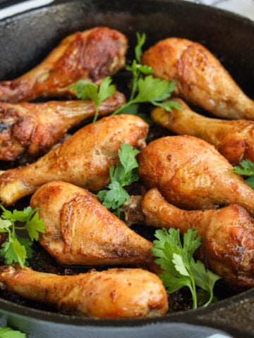 Baked Chicken Drumsticks in a cast iron skillet with parsley.Baked Chicken Drumsticks in a cast iron skillet with parsley.
