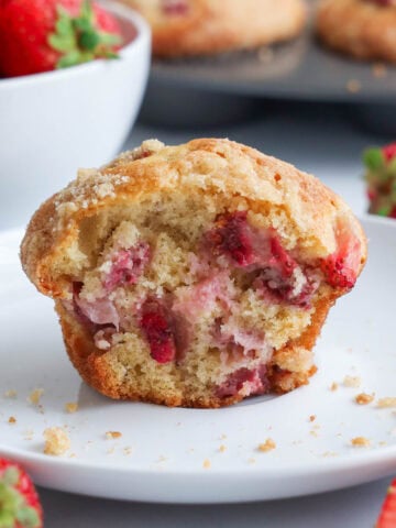 Strawberry Muffin broken in half on a plate with crumbs.