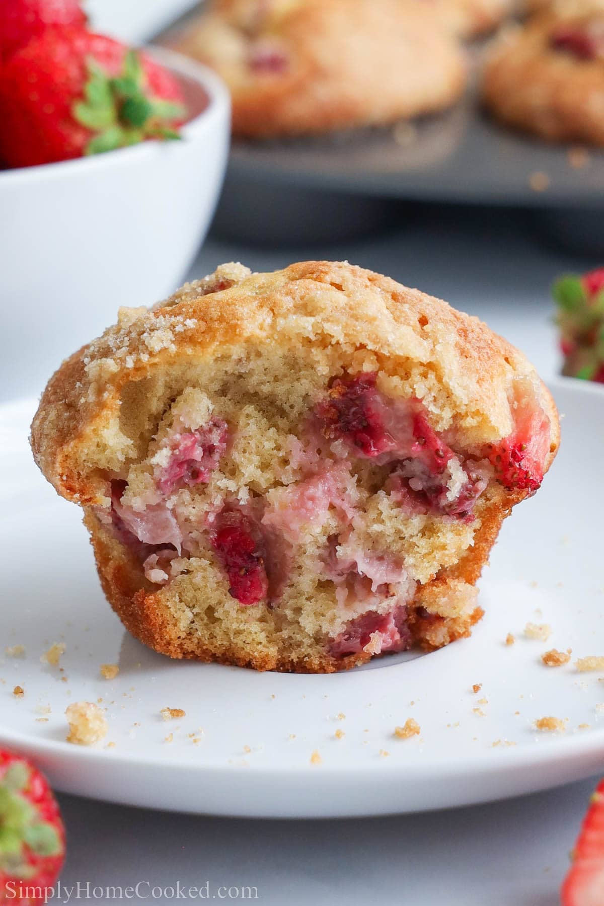 Strawberry Muffin broken in half on a plate with crumbs.