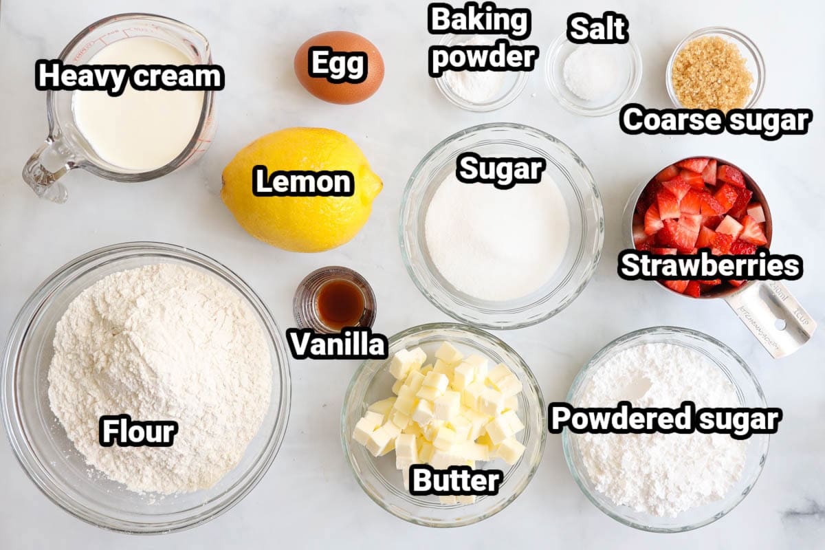 Ingredients for Strawberry Scones: flour, butter, heavy cream, lemon, egg, vanilla, powdered sugar, granulated sugar, baking powder, salt, coarse sugar, and strawberries.