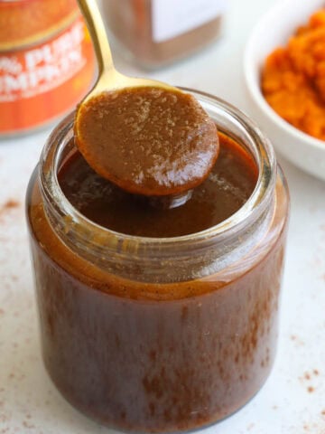 Pumpkin Spice Syrup in a jar with a spoon.