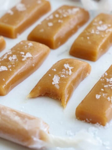 Soft Caramel Candy, cut into pieces and topped with sea salt, one missing a bite.